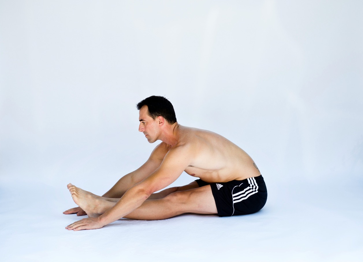 Person doing a seated forward fold stretch, working toward touching their toes